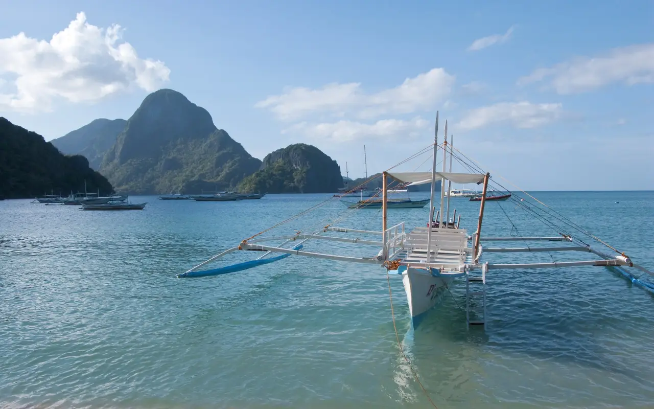 A traditional bangka outrigger boat moored in clear water off El Nido, Palawan