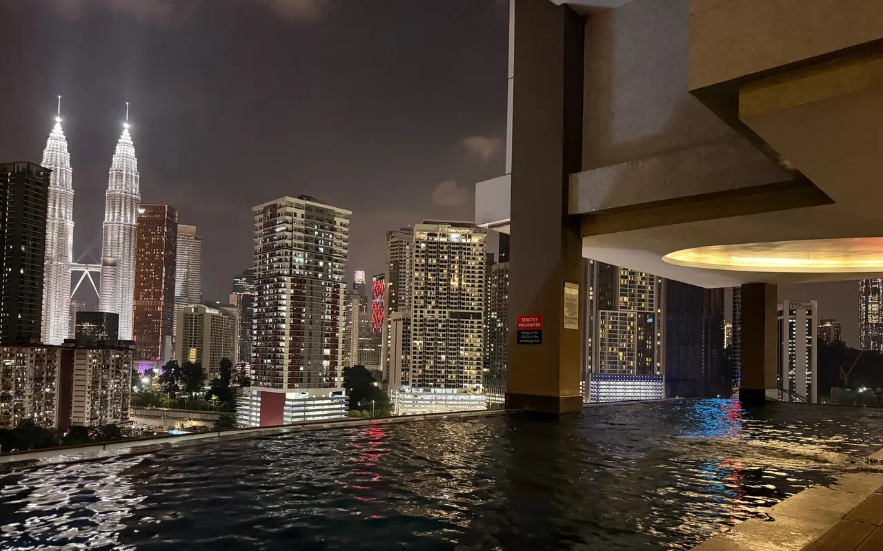 A rooftop infinity pool at night looking out to the Petronas Towers
